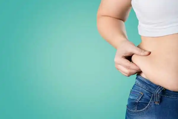 Image of woman pinching her love handles to show weight gain Nottingham